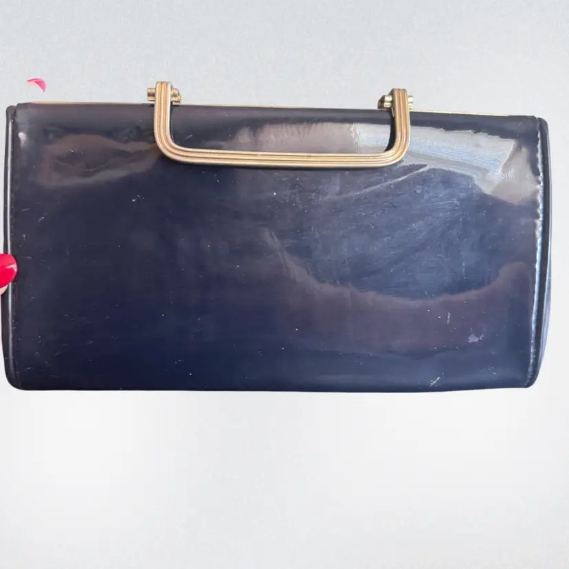 A vintage navy patent leather clutch purse with a gold-tone frame. 9x5”