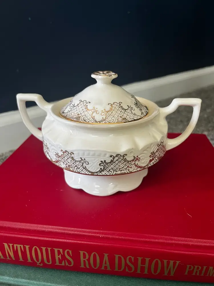 A beautiful vintage white porcelain sugar bowl with intricate gold filigree.