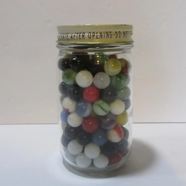 lot of vintage glass marbles in glass jar with vegetable salad recipe top