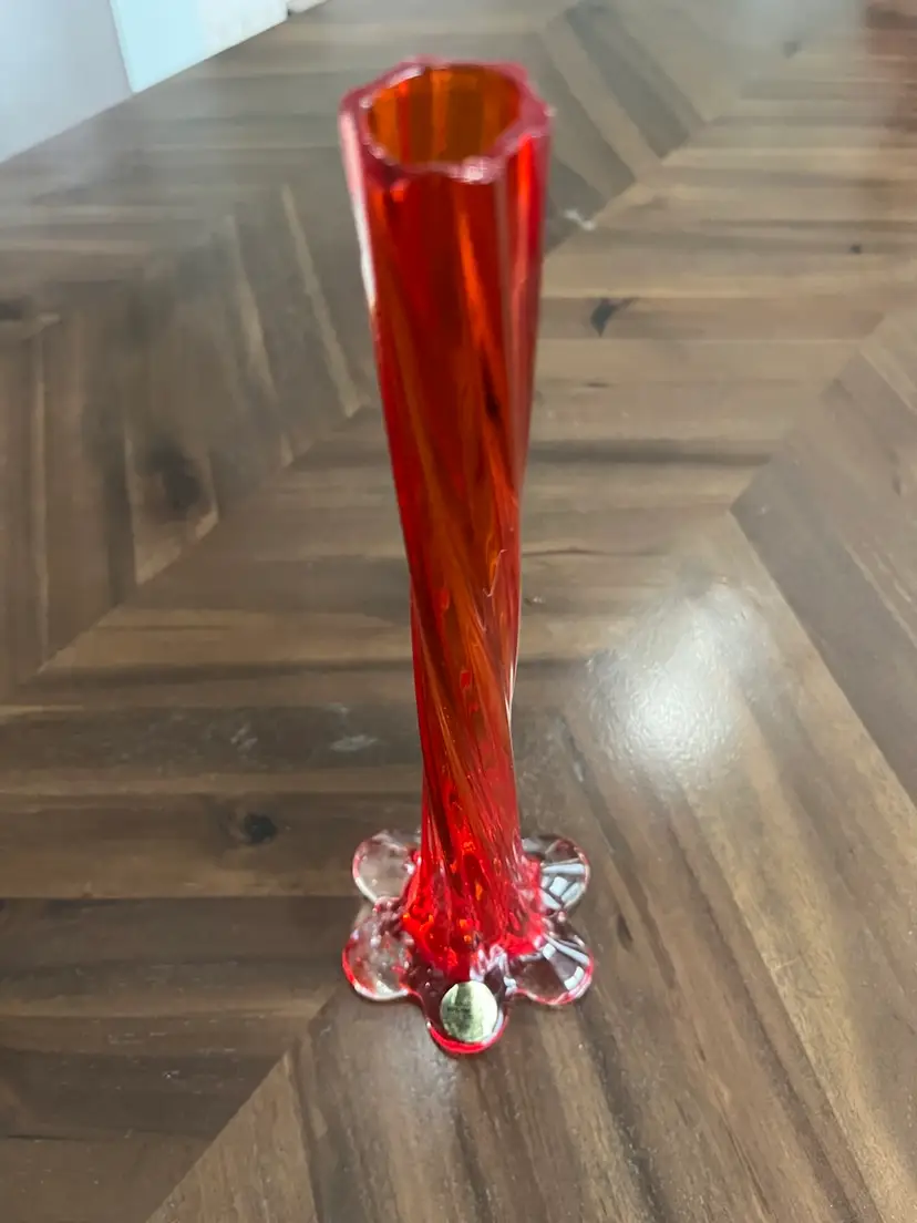 Orange-red twisted glass bud vase with a clear petal base. 11.25” Tall