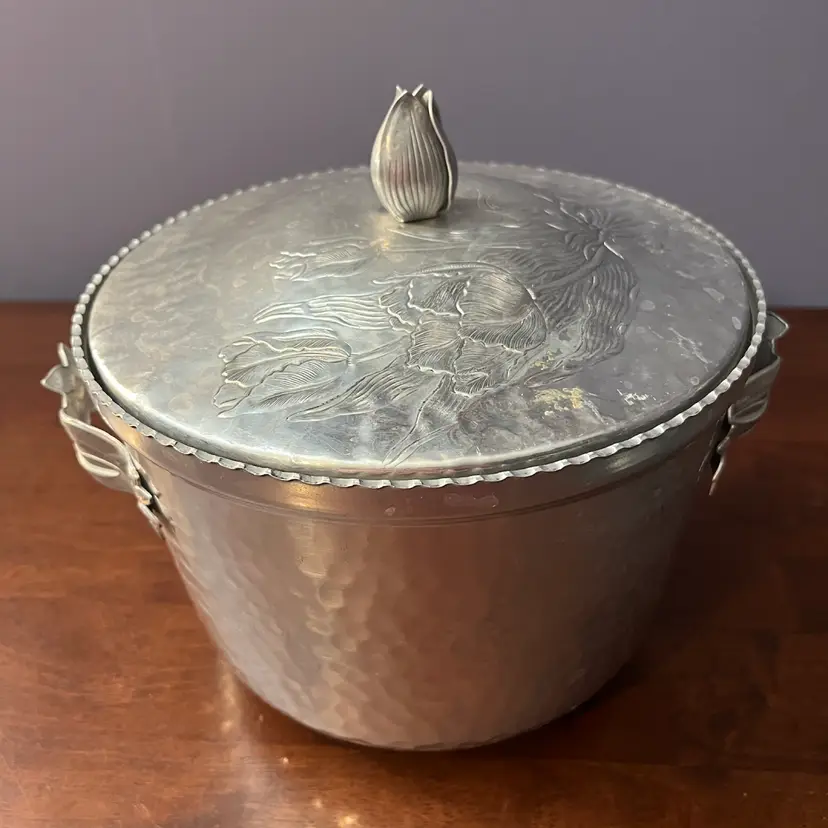 Vintage hammered aluminum ice bucket with floral motifs and tulip bud lid. 8” H X 
6.5” Circa 1950s