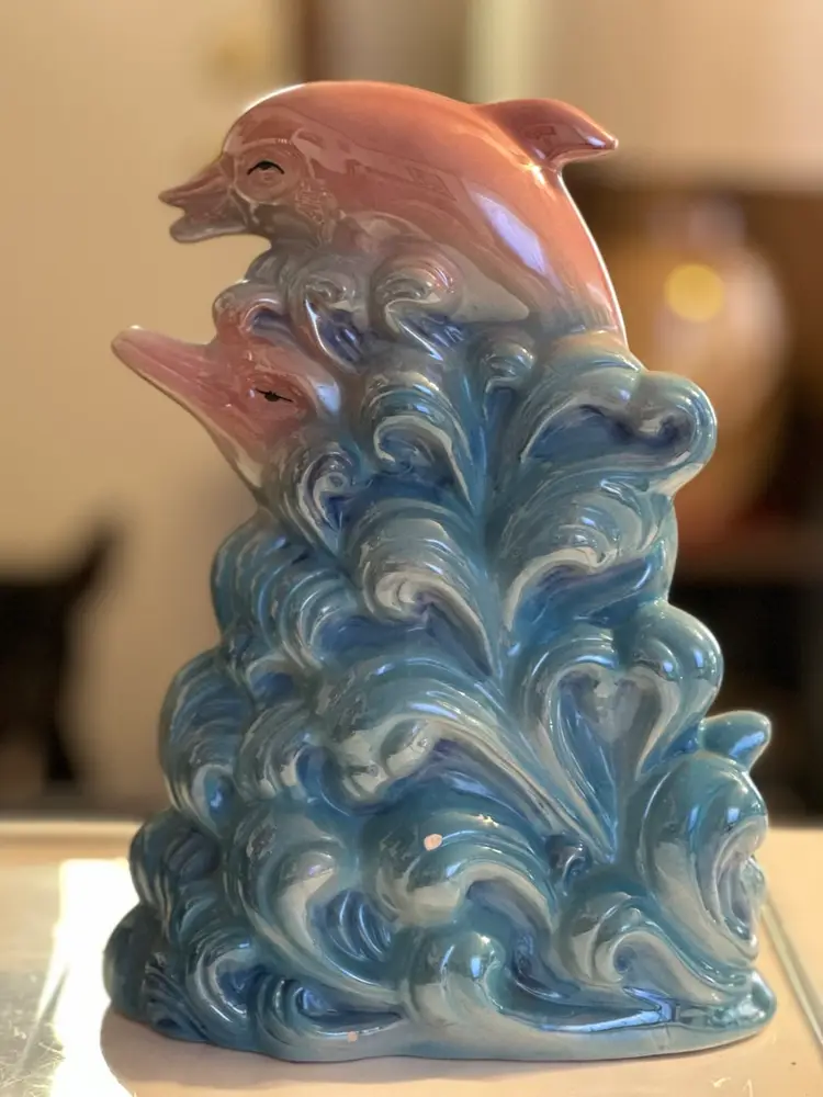 Porcelain figurine of dolphins leaping through waves.