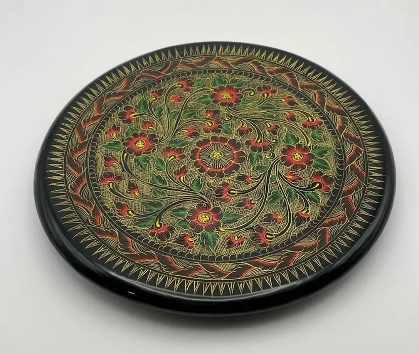 Black lacquer, 8” wooden plate, hand painted in gold/green/red florals and decorations. Excellent Condition!