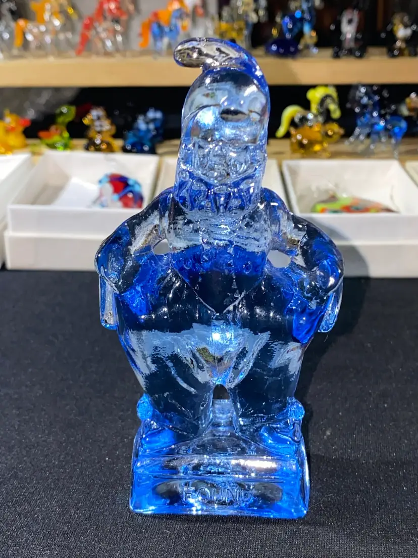 #03- Mosser Glass Co. This is part of the Series -  SO GLAD I FOUND YOU AT THE END OF THE RAINBOW - MINDY.  The Jester Style Clown is 4.75" Tall. He is a clear Light Blue color. 1983