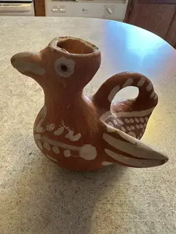 Terracotta bird-shaped pitcher with white painted decorations.