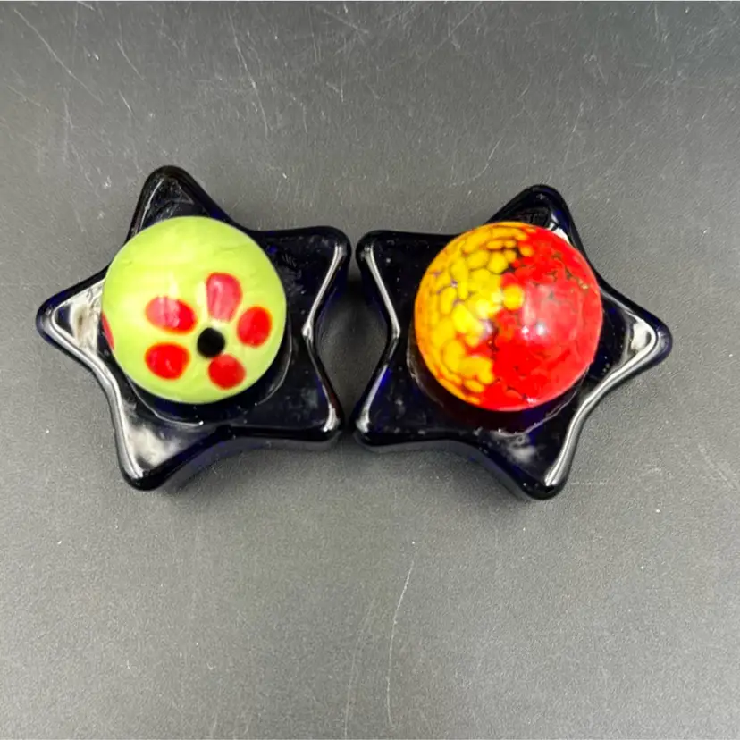 A Set Of Two Marbles, One With Floral One With Orange And Yellow, And A Set Of Stars Royal Blue Glass.
