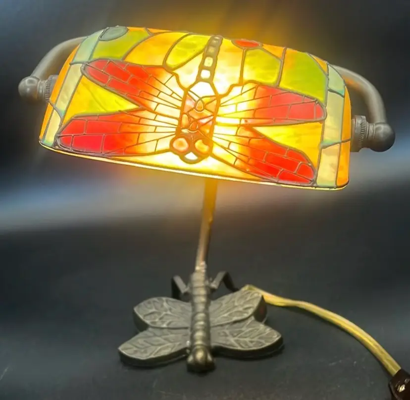 Vintage Tiffany-style desk lamp features a stained glass banker-style shade with a red and yellow dragonfly design