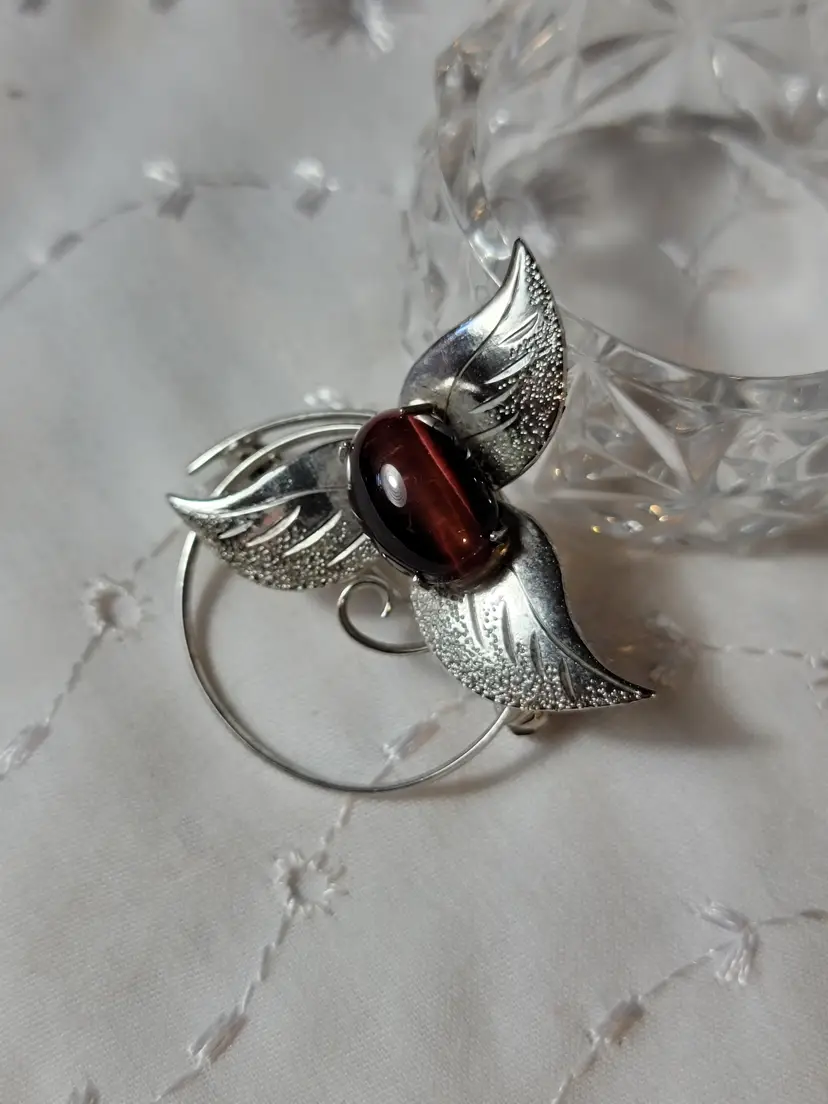 Silvertone leaves surrounding a redish purple stone