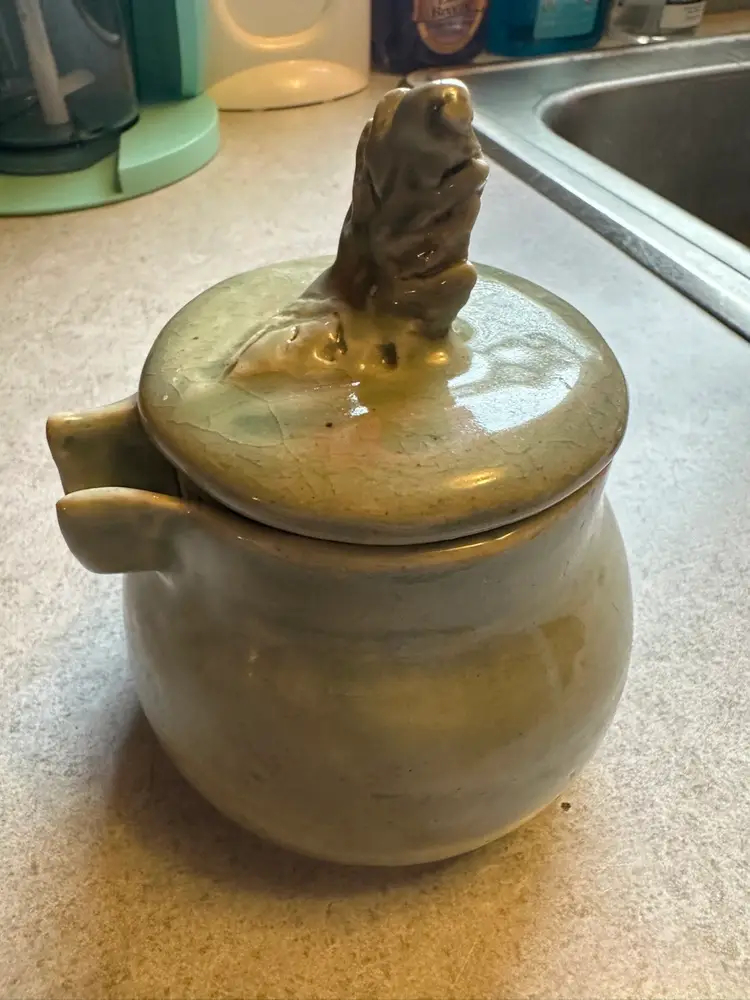 Ceramic honey pot with leaf-shaped lid finial.