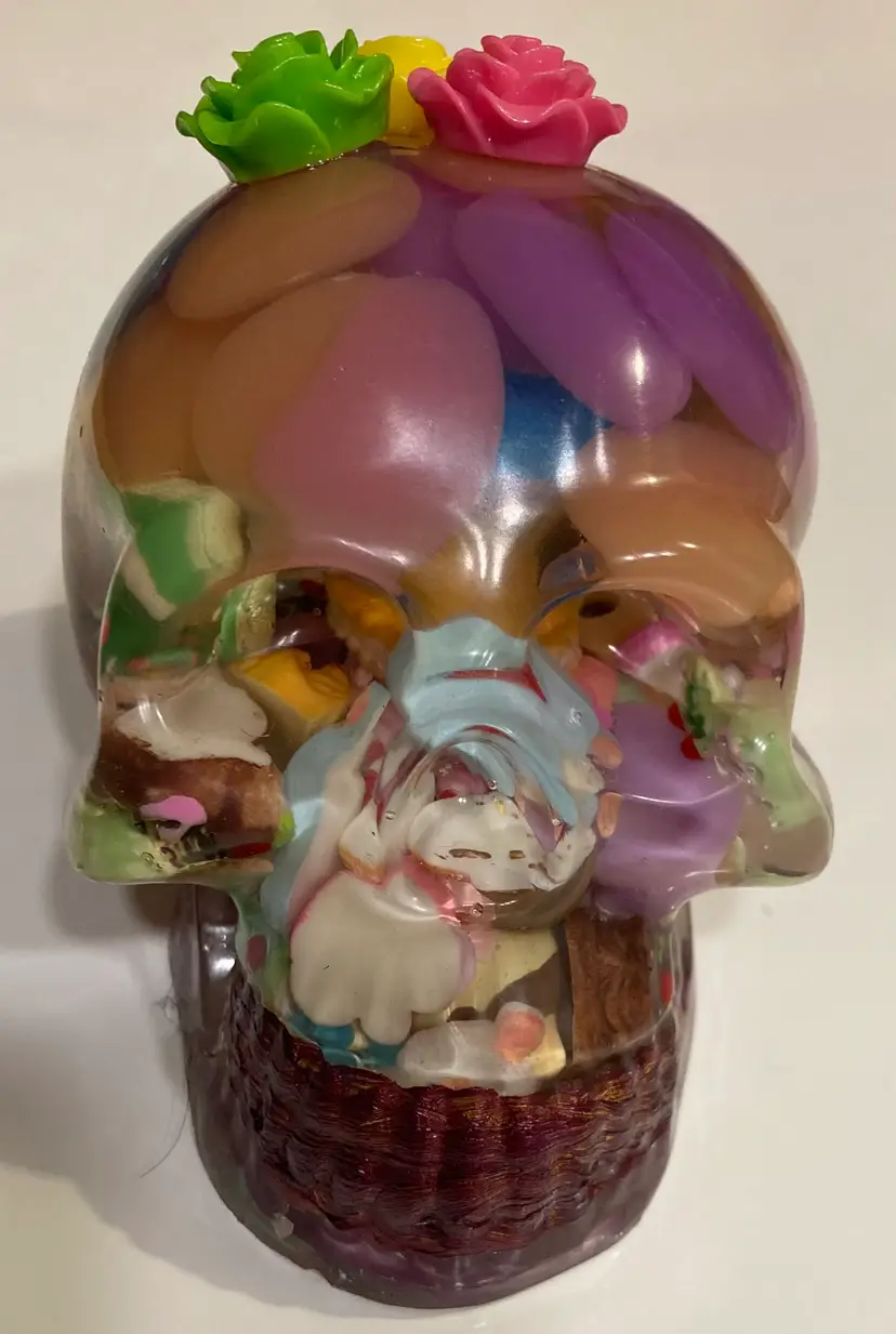 Multicolored pastel resin skull figure paperweight with faux desserts and flowers