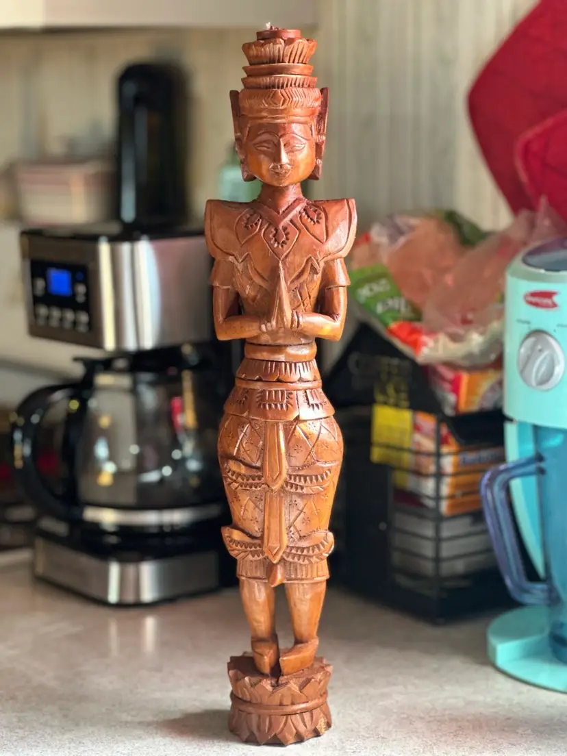 Wooden carved Thai Buddhist deity figure in prayer pose.