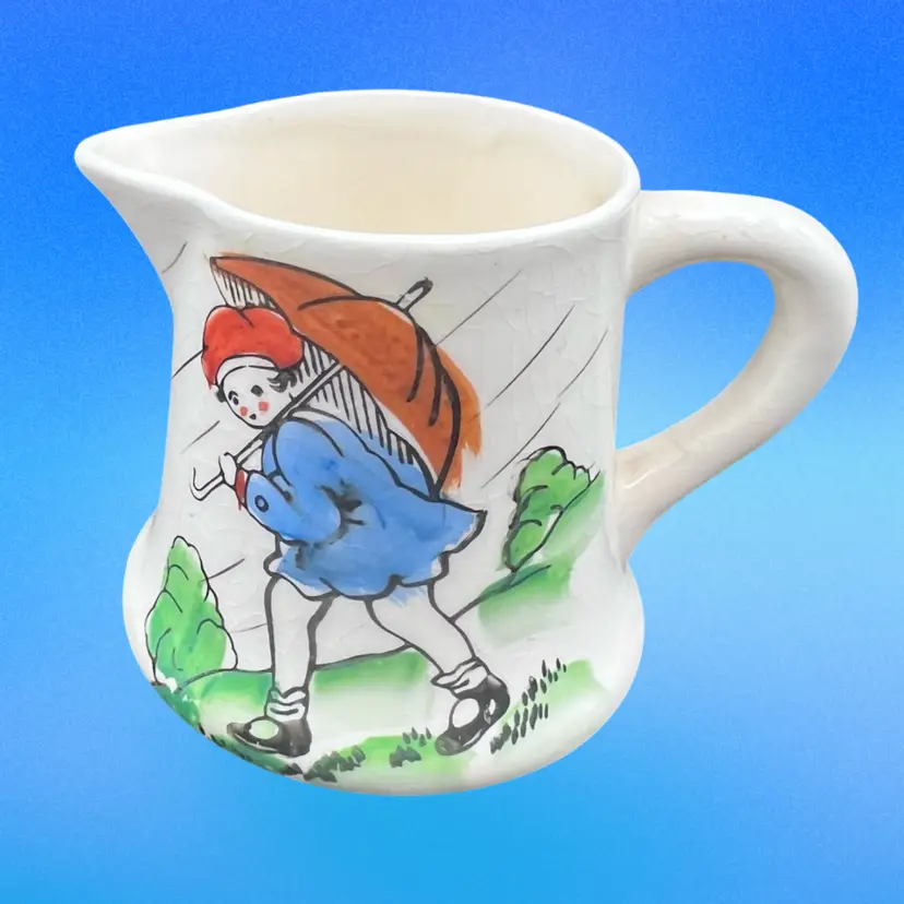 #145B Vintage Ceramic Creamer With Nursery Rhyme Theme Of A Little Boy Or Girl In The Rain With An Umbrella. Made In Japan