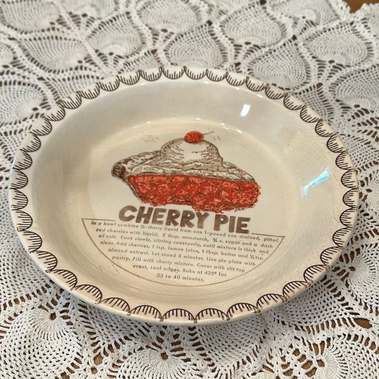 The Vintage Cherry Pie Plate Baking Dish is a charming addition to any kitchen collection, featuring a round ceramic piece with a colorful cherry pie design. This unique pie dish includes a cherry pie recipe, with its 10 1/4”diameter and 1.5" depth, this original piece from the 1980s is A Great nostalgic piece.  There is some crazing and a Small chip on the back shown in pictures.