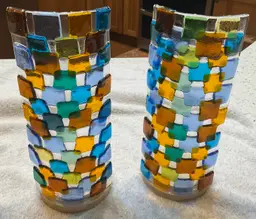 #01 Two fused glass candle holders. 9.5” tall and 5” wide the fused pieces are attached to wood bases 3 3/4” round. Will accommodate large pillar candles.
