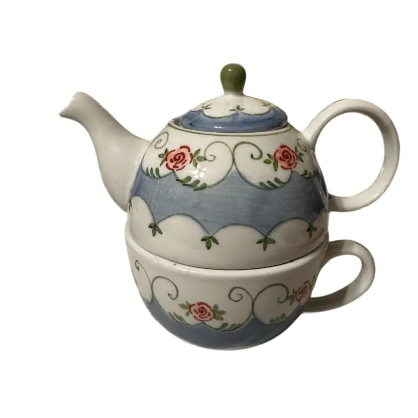 A modern ceramic teapot and cup set with hand-painted roses.