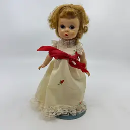 Vintage Madame Alexander Collectible Doll Hard Plastic Sleep Eyes Strawberry Blond Hair Moveable Arms & Legs Marked ALEX in Back Off White Dress W/ Embroidered Strawberries Or Rose Buds Red Ribbon Comes With Schmid Doll Stand