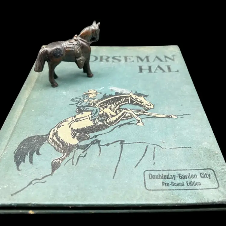 Vignette #1 Vintage Copy Of Horseman Hal Written And Illustrated By Sanford Tousey Along With A Bronze Miniature Horse/Pony With Saddle Figurine Marked Made In Japan. Also Included Is A Beautiful Wooden Tinker Box With A Horse Head Carved/laser Etched On The Top Lined With Blue Velvet 
The Book Shows To Be A Pre-Bound Edition, Hardcover Doubleday Publishing Copyright 1950 
Some Pages Have Writing Or School Stamps As It Was A Discarded Library Book Last Checked Out In 1980 
Illustrations Are Bright And Colorful.