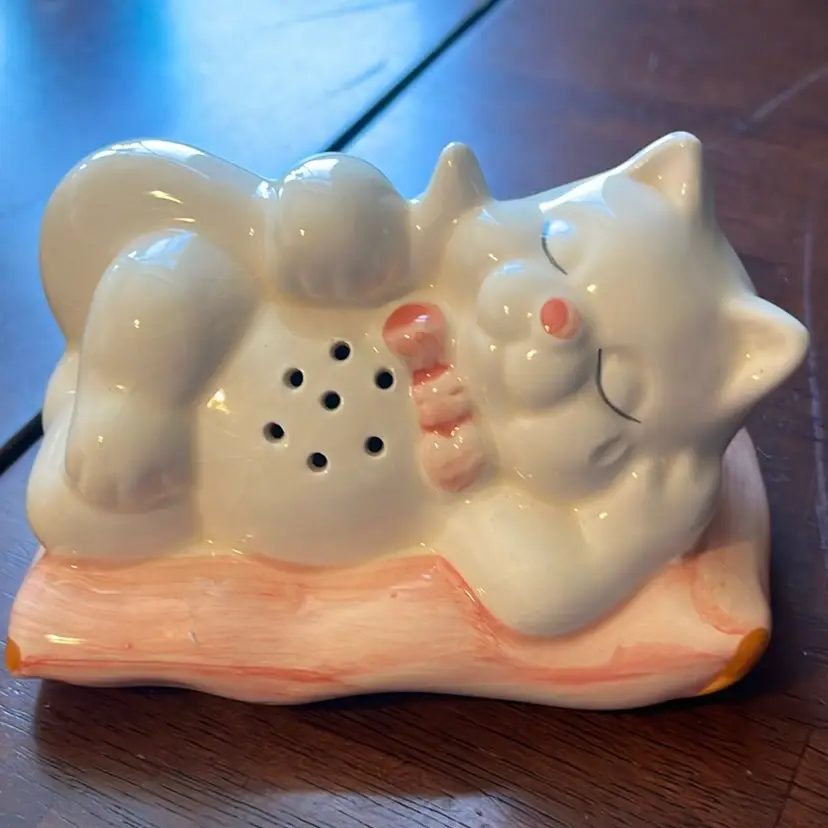 This is a vintage Interpur ceramic sleeping cat shaker with a pink bow. 5”x3”