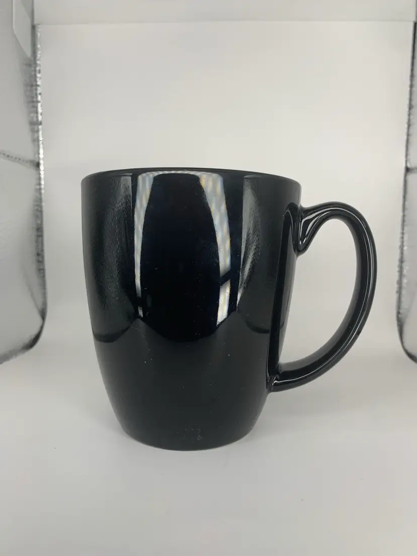 Corelle Stoneware Black Coffee Mug by Corning, H: 4”L: 5 1/2” W: 3 1/4”.