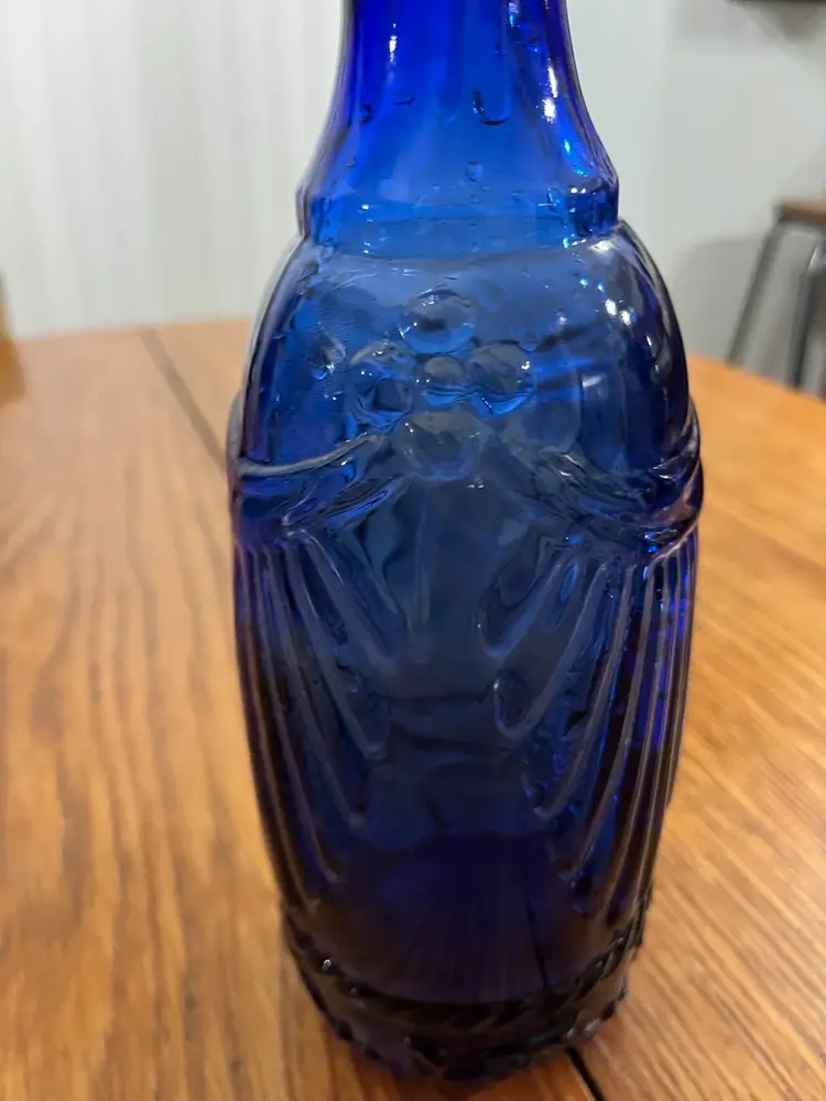 Cobalt blue glass bottle with embossed fan-shaped drape pattern.11”