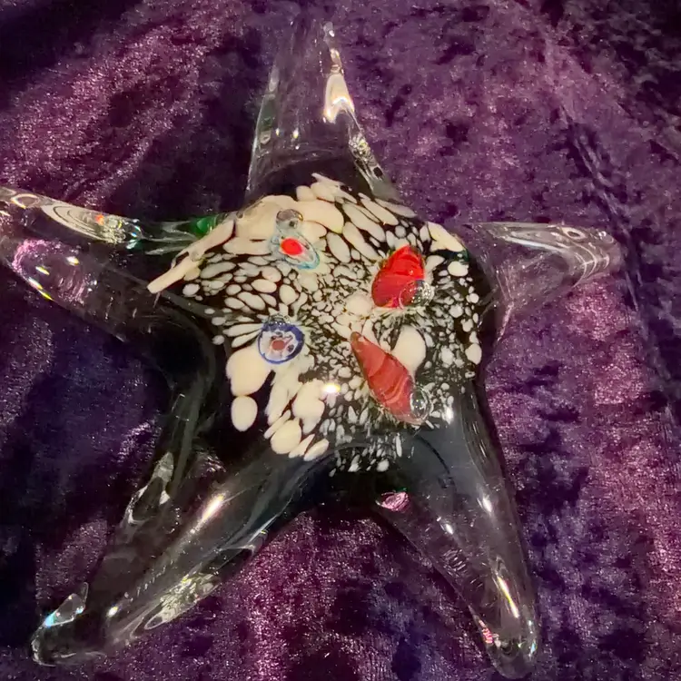 Murano-style art glass starfish paperweight, featuring a clear body with an internal millefiori design. Approximately 5.5” Wide