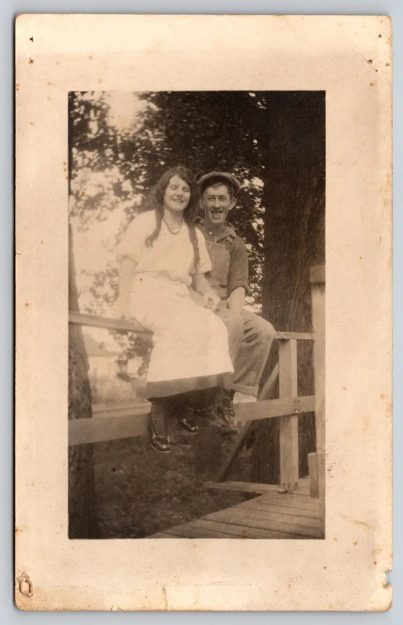 Postcard RPPC Man and Woman Sitting on Fence Real Photo Overalls Braids - 9281