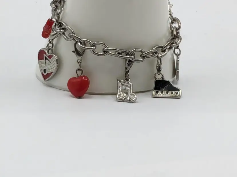 Charm Bracelet Musical Theme Silver Tone Piano Hearts Notes
Good condition.  Each charm has a lobster clasp.  Red acrylic star is worn around the edges. Silver, red, black, white colour scheme.  Measures 6 3/4".