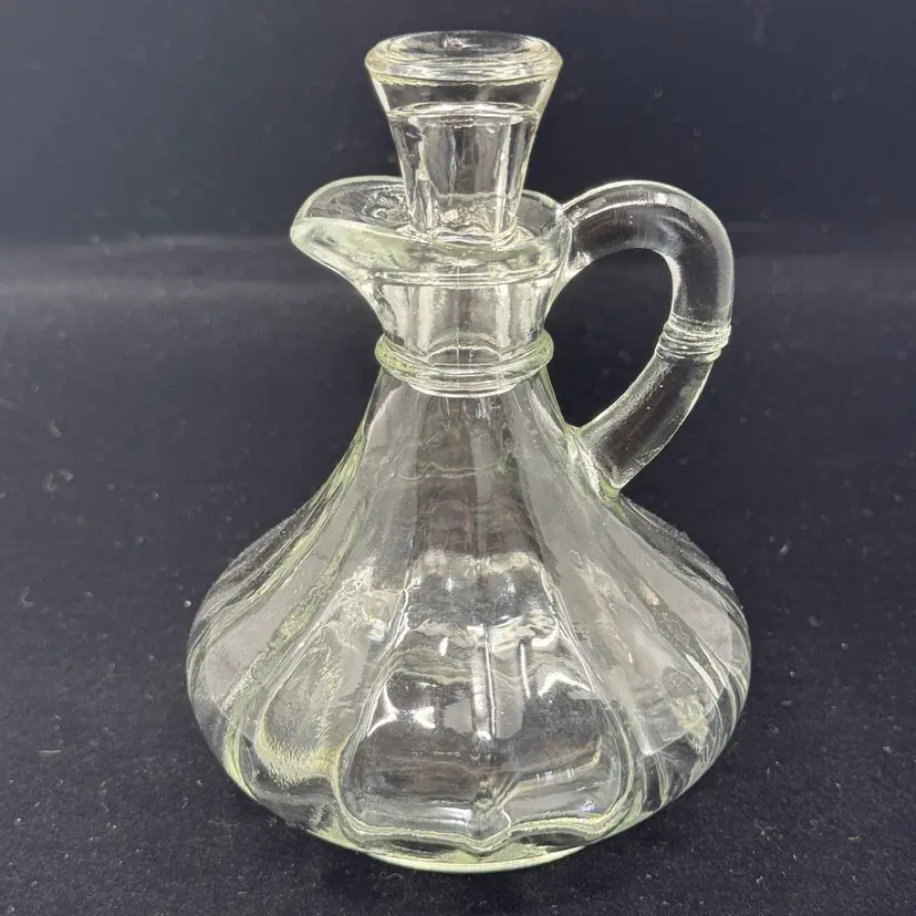 A vintage clear glass cruet with a ribbed body and glass stopper.