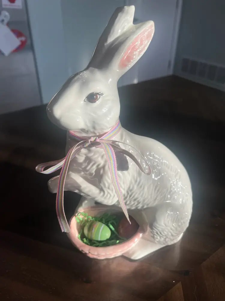 A ceramic Easter bunny figurine holding a basket of eggs.  10.5” Tall