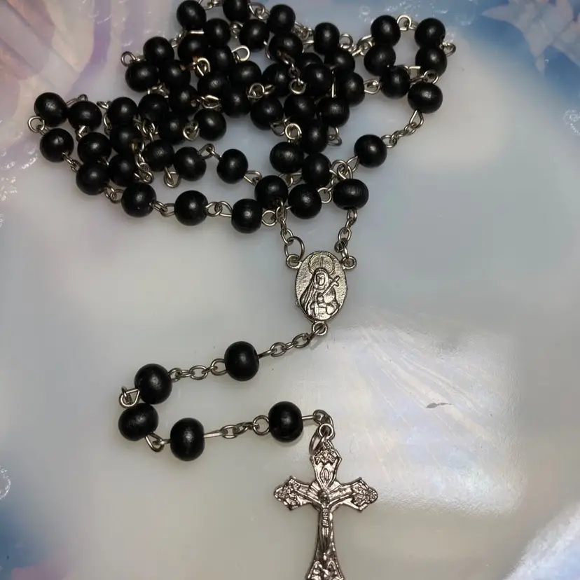 Rosary with Black Beads and Silver Tone Chain and Crucifix With Jesus. 
Silver Tone Mary, With The Anointing Hallow, Pendant,  On One Side Holding A Cross And 5 Cross Symbol On The Opposite Side Of The Pendant. 
Absolutely Stunning!