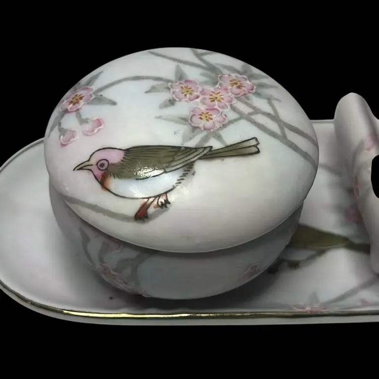 Read - A Beautiful Small Vanity Set With An Under Plate And Two Trinket Dishes. Elegantly Hand Painted Cherry Blossoms And A Colorful Bird. So according To My Research These Pieces Would Date Back To 1921 Or Earlier. I Also Concluded That Someone At Sometime Didn’t Know What Or Where They Were Made And This Why We See Shiny “New” Made In China Stickers Attached. The “M” Inside The Wreath Means Morimura Bros. Technically These Are Considered Antique Instead 
Of Vintage.