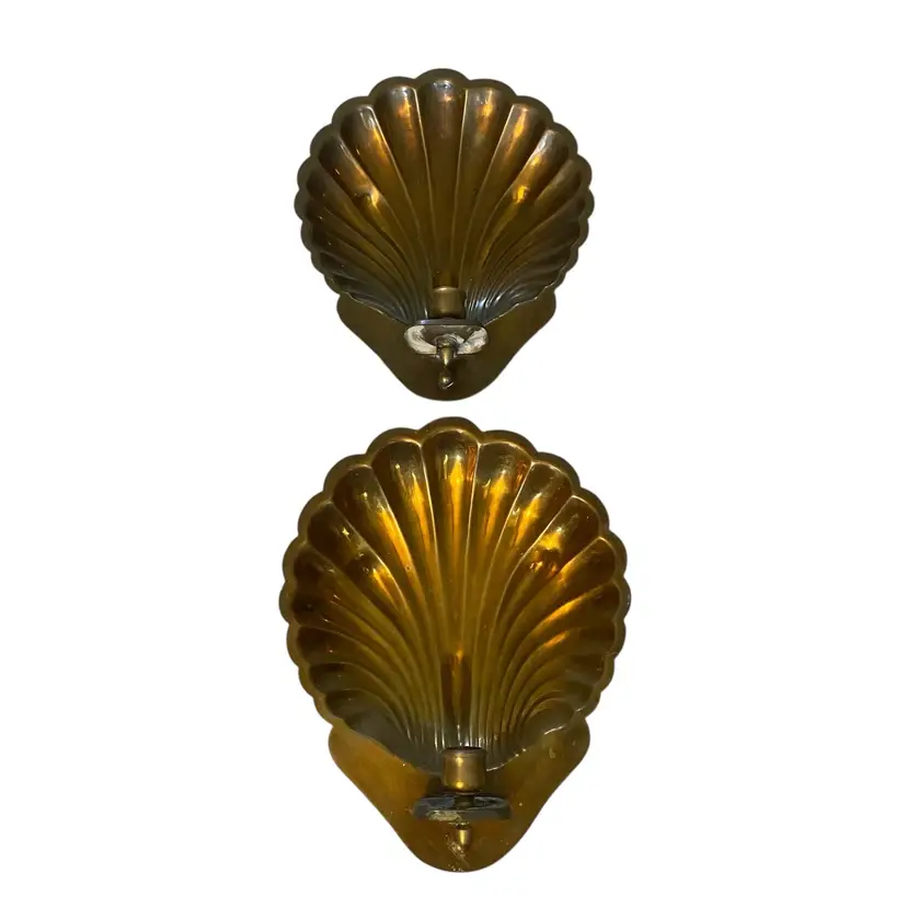 These vintage brass scallop shell wall sconces are often found in Hollywood Regency style decor from the 1950s. They are typically designed for taper candles and are cast from brass in a clam shell form