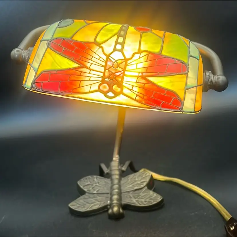 Vintage Tiffany-style desk lamp features a stained glass banker-style shade with a red and yellow dragonfly design