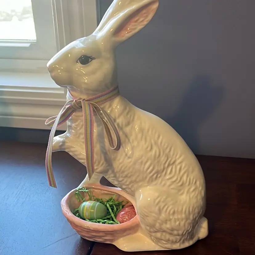 A ceramic Easter bunny figurine holding a basket of eggs.  10.5” Tall