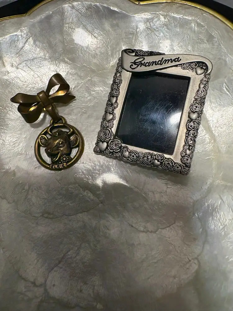 Vintage brass Elsie the Cow bow brooch and a silver-toned "Grandma" photo frame with rose and heart motifs Brock / Stand