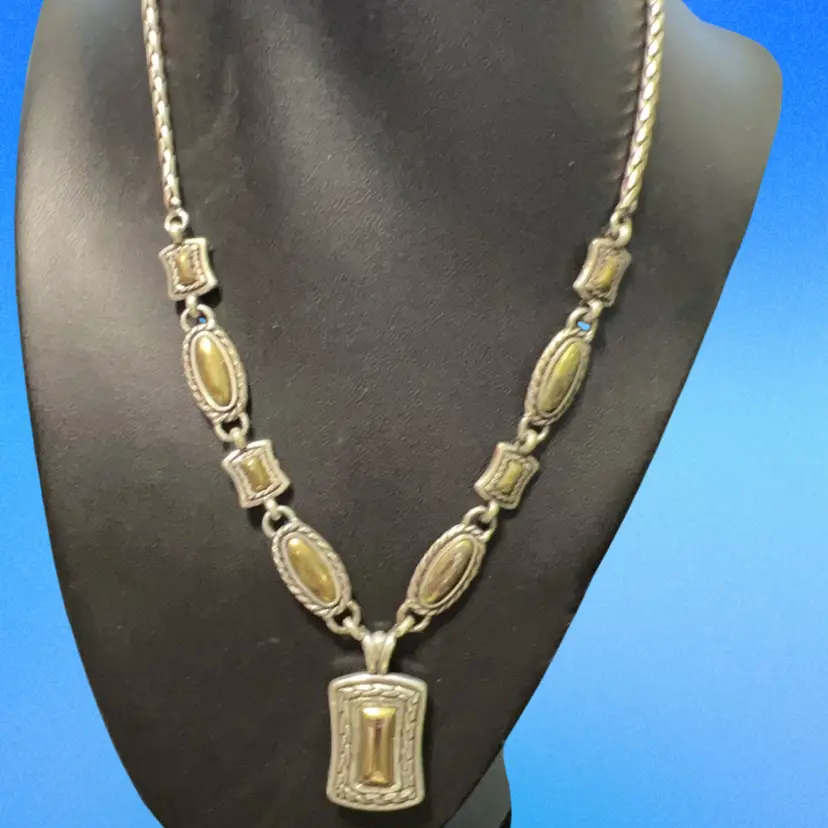 This vintage Brighton necklace features a distinctive two-tone design with a large rectangle pendant and alternating oval charms