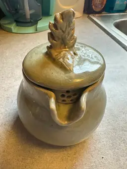Ceramic honey pot with leaf-shaped lid finial.