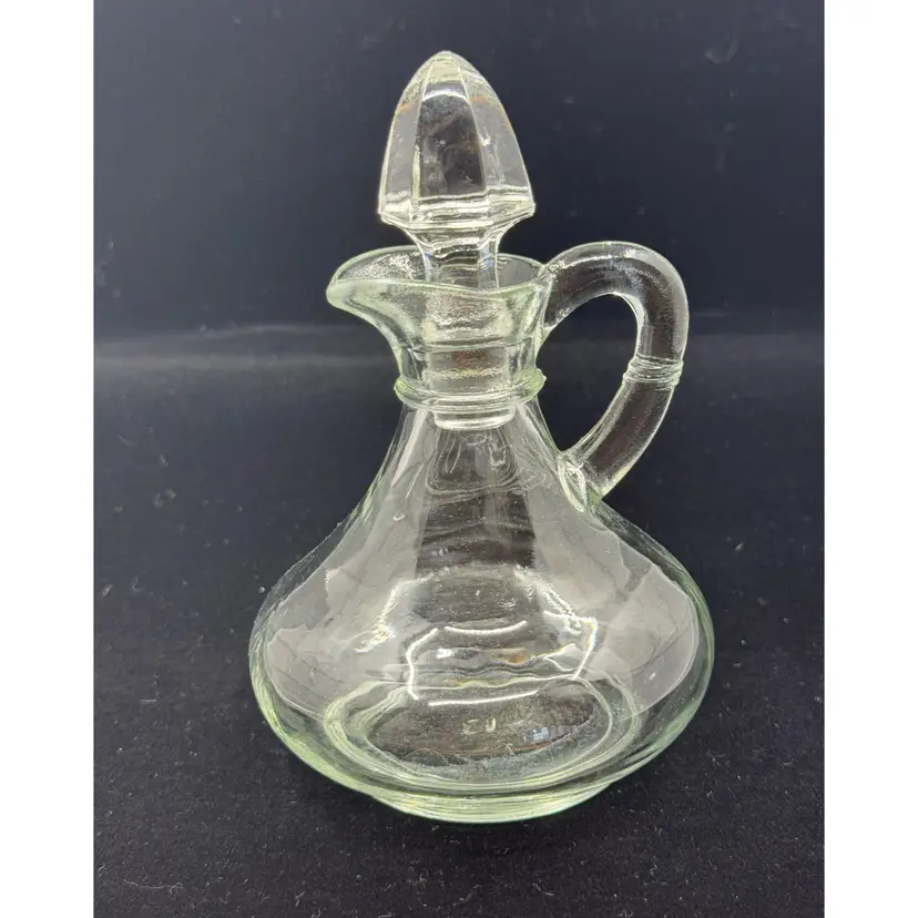A vintage clear glass cruet with a ribbed body and glass stopper.