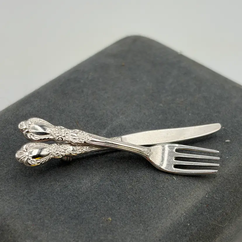 Vintage silverware-style brooch pin featuring a miniature crossed fork and knife