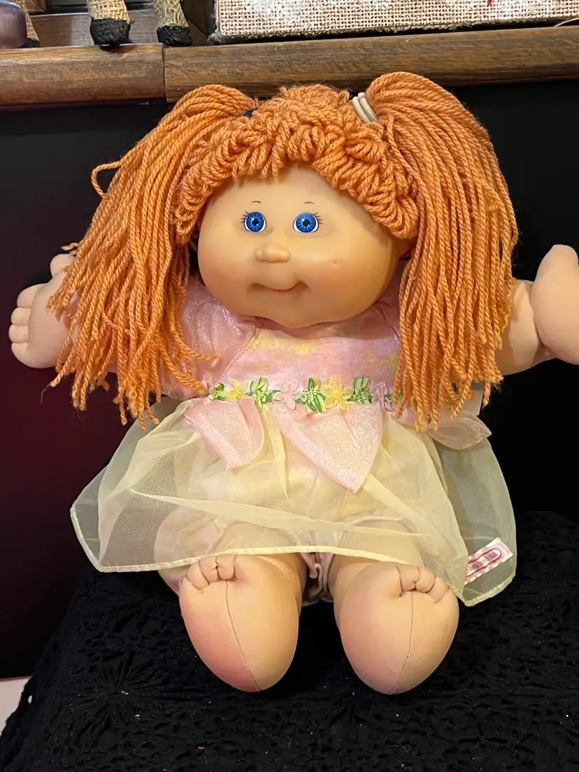 #01 Vintage Cabbage Patch Kid. With Ginger Colored Hair in Pigtails & Blue Eyes. Dressed in a Yellow & Pink Tulle Dress w/ Pink & Yellow Pantaloons