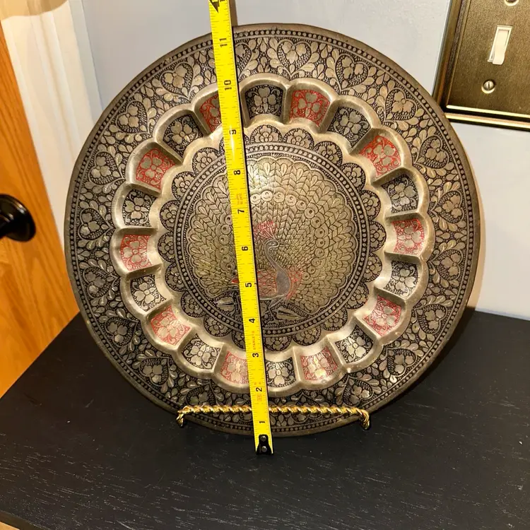 Vintage decorative brass plate with a peacock design.