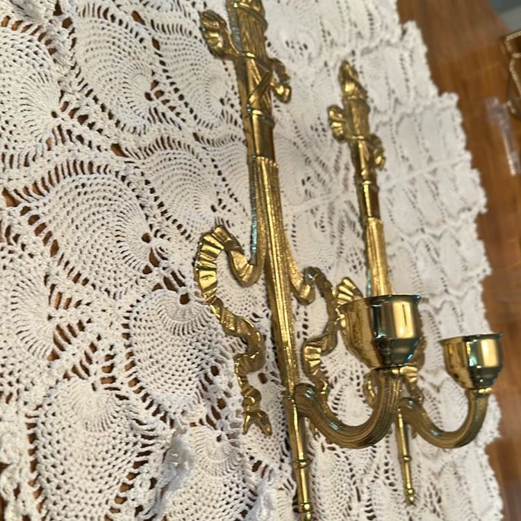 Vintage brass wall sconce Pair, often referred to as a "torch and ribbon" style candle holder. These were made by The Bombay Company, dated 1992. Elevate your home decor with these stunning vintage Bombay brass wall sconces. The intricate carvings and antique brass finish add a touch of Hollywood Regency style to any room.