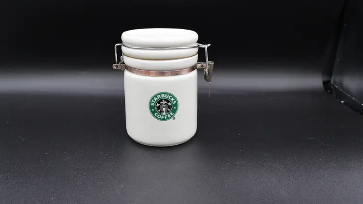 Starbucks 2007 small white ceramic jar coffee tea 5” air seal latch has some rust and discoloration on the metal.