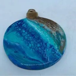 Handmade round resin Hanging Ornament with a blue and brown marbled design.