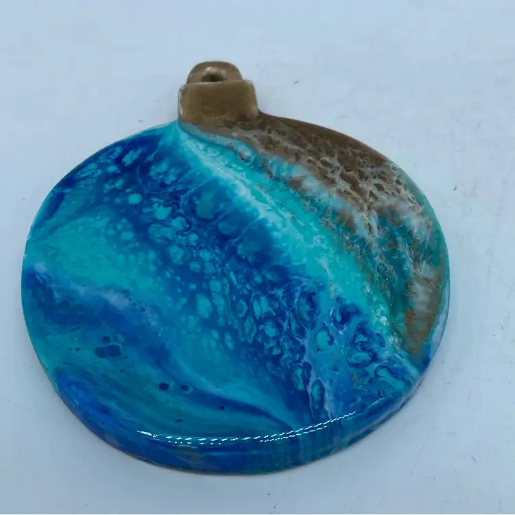 Handmade round resin Hanging Ornament with a blue and brown marbled design.