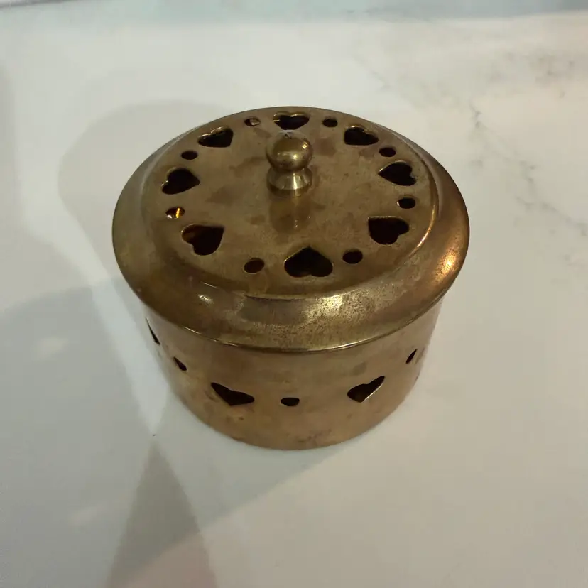 Vintage pierced brass potpourri container with heart cut-outs.