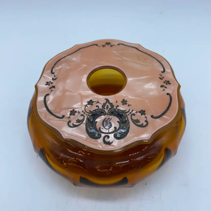 #4210 Vintage amber glass hair receiver with decorative celluloid lid and crest.