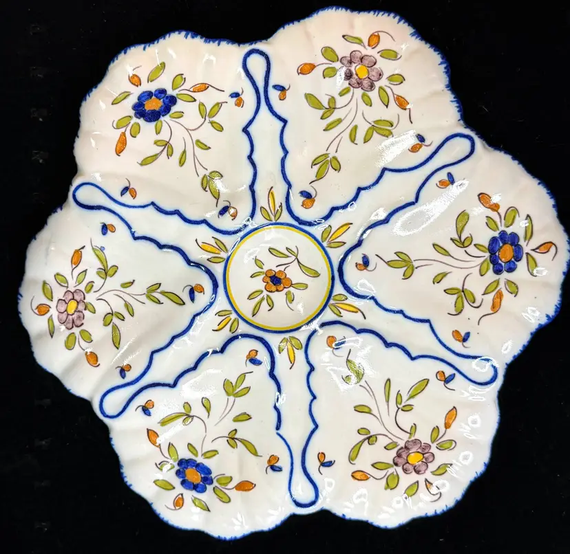 Beautiful vintage French faience oyster plate from Martres-Tolosane, decorated in the Moustiers style with six molded oyster wells surrounding a floral center medallion. Hand-painted cobalt blue outlines are accented with green, orange, yellow and soft lavender flowers on a creamy white ground. The scalloped form and raised shell-shaped wells give the plate wonderful dimension. The underside is hand-marked “Martres.” Comparable Martres-Tolosane oyster plates are generally attributed to around the 1940s.  Size: Approx. 9.75" Material: French glazed faience Origin: Martres-Tolosane, France Style: Moustiers Era: Circa 1940 Condition: Mint vintage condition with no chips, cracks or repairs observed SKU: A1249 Price: $295