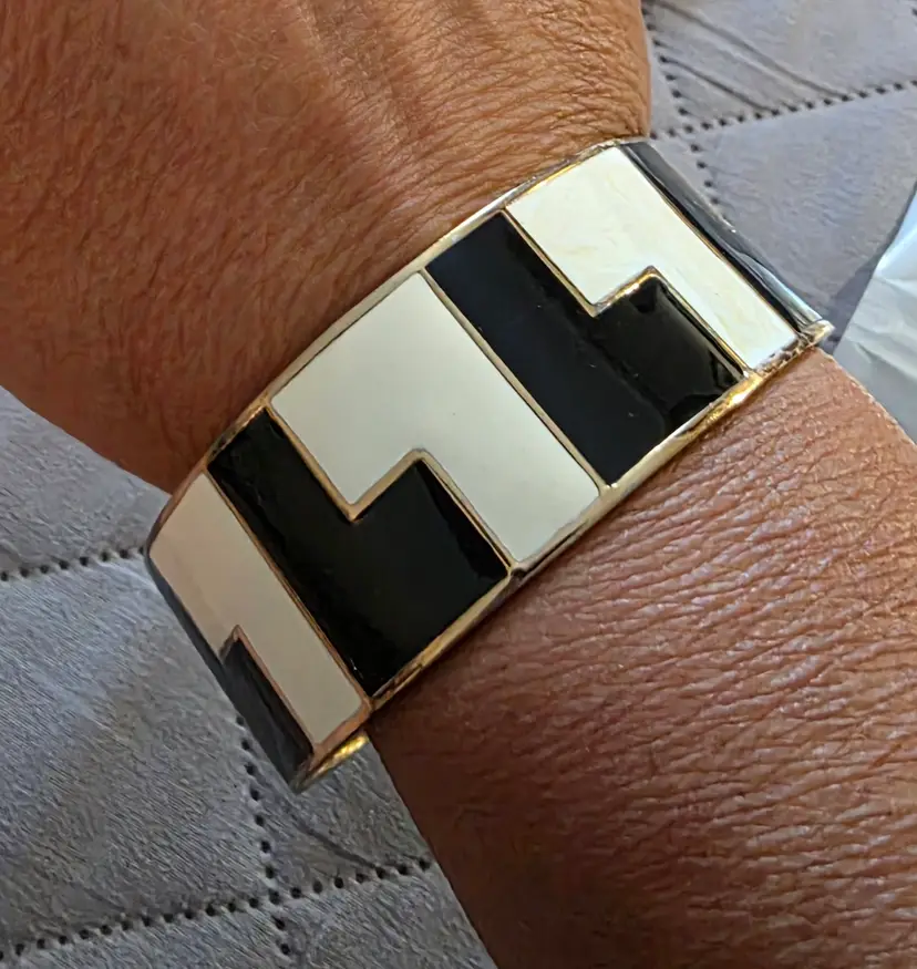 VIntage L.A.M.B. by Gwen Stefani wide cuff bracelet featuring a bold geometric black-and-white enamel pattern with gold-tone trim. [1] (https://www.cafr.ebay.ca/itm/145037773909), [2] (https://www.worthpoint.com/worthopedia/gwen-stefani-black-white-enamel-gold-1725958267)