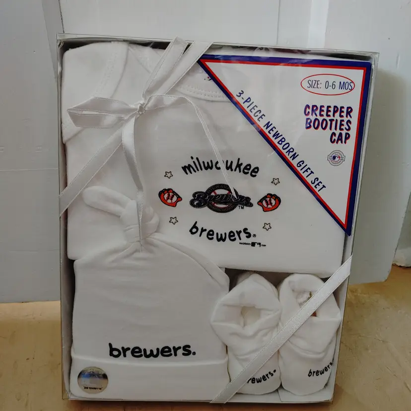 #01 Kids- Brand: HAG. Size 0-6 months. 3 piece set- creeper, booties, cap. New in box. Milwaukee Brewers sport set. Material- 100% cotton. No callouts.